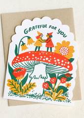 Greeting card with two gnomes holding hands under a mushroom, surrounded by flowers and text 'Grateful for you'.