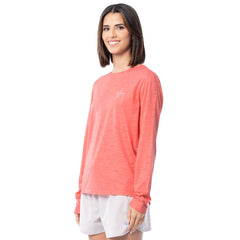 Woman wearing a coral long-sleeve shirt and white shorts on a white background