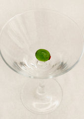 Clear martini glass with a glass olive decoration inside.