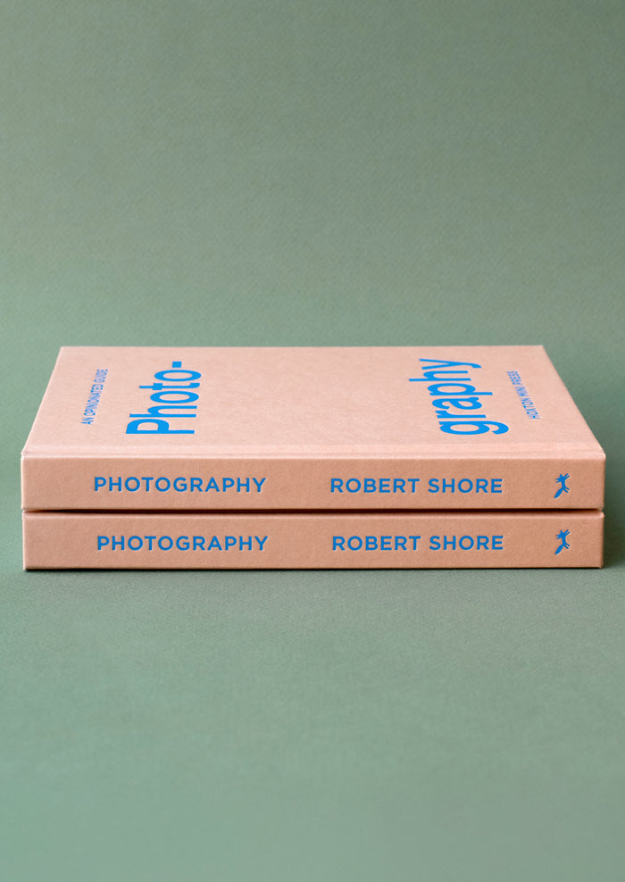 A pink hardcover book with blue lettering titled "An Opinionated Guide To Photography".