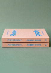 A pink hardcover book with blue lettering titled "An Opinionated Guide To Photography".