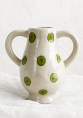A ceramic vase in green dot pattern with side handle detail.