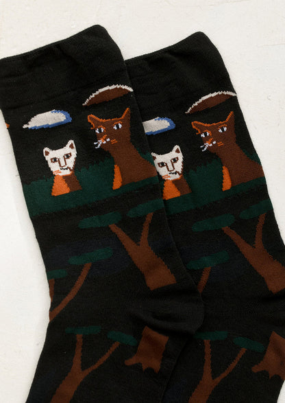 A pair of black socks with cat and tree print.
