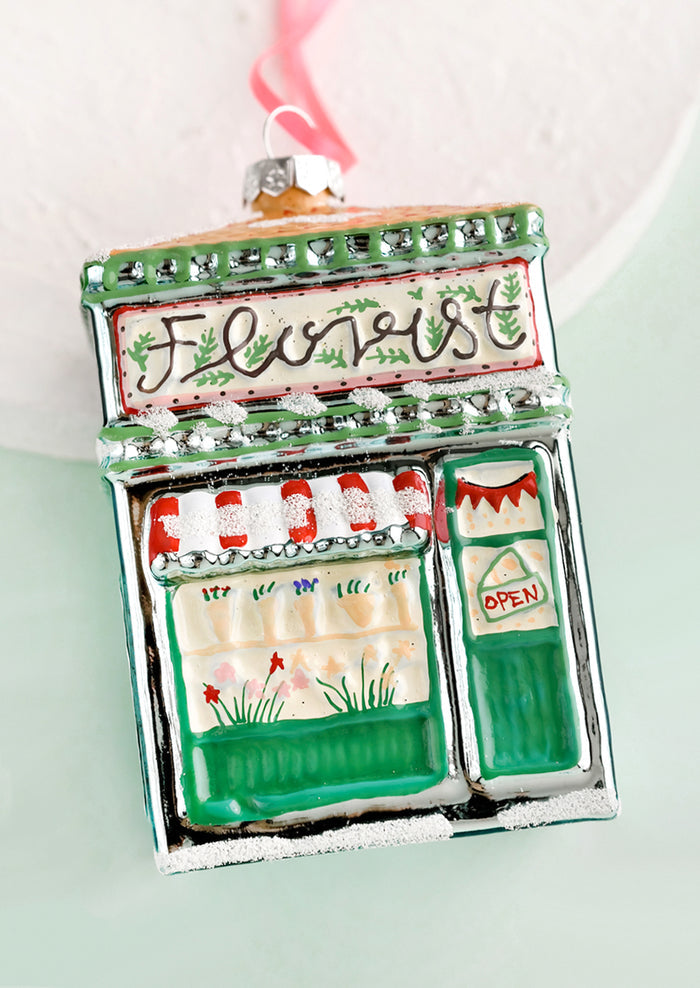 A glass holiday ornament in shape of florist shop building.