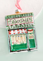 A glass holiday ornament in shape of florist shop building.