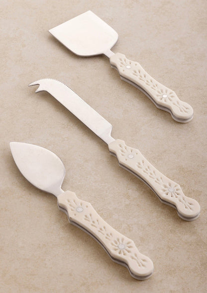 Three different cheese knife styles in silver with eyelet detailed cream resin handles.