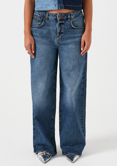 A woman wearing a pair of wide leg jeans in classic medium blue wash.