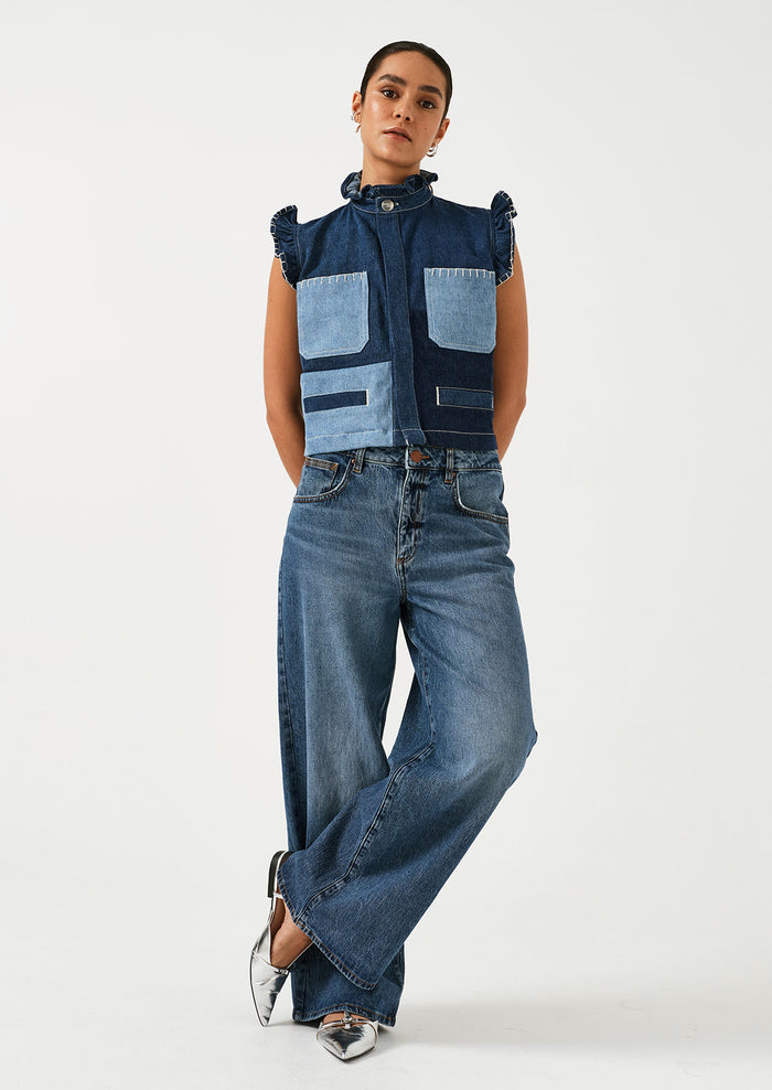 A woman wearing a pair of wide leg jeans in classic medium blue wash.