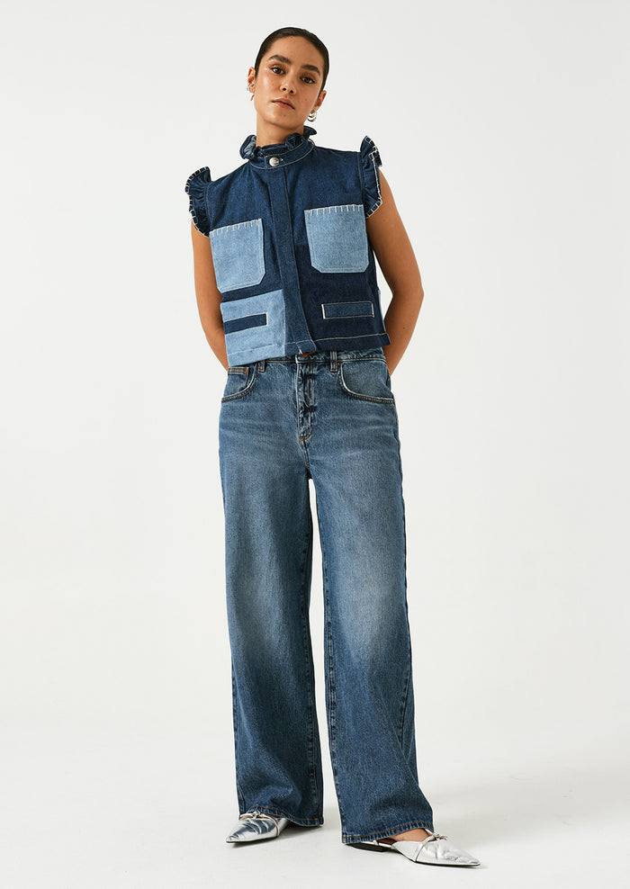 A woman wearing a pair of wide leg jeans in classic medium blue wash.