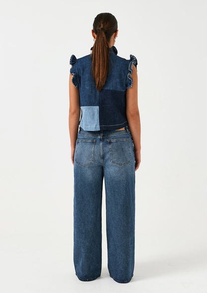 A woman wearing a pair of wide leg jeans in classic medium blue wash.
