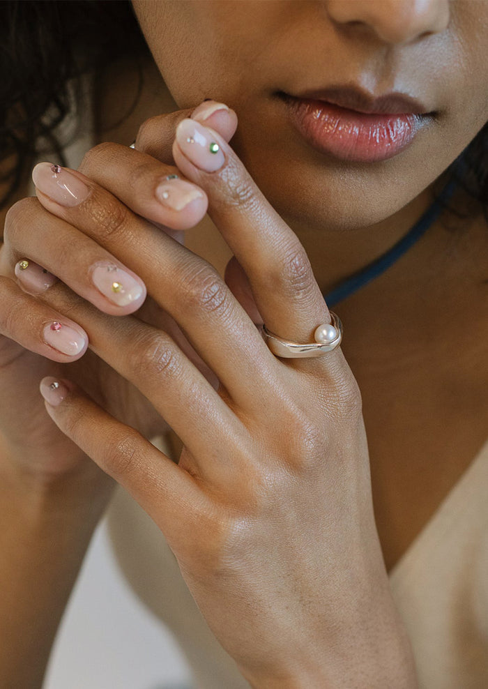 A woman wearing a sterling silver ring with inner pearl detail.