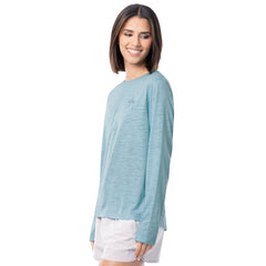 Woman wearing a light blue long-sleeve shirt and white shorts on a white background