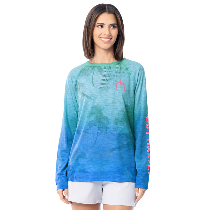 Woman wearing a blue and green gradient long-sleeve shirt with a red  Guy Harvey logo on a white background