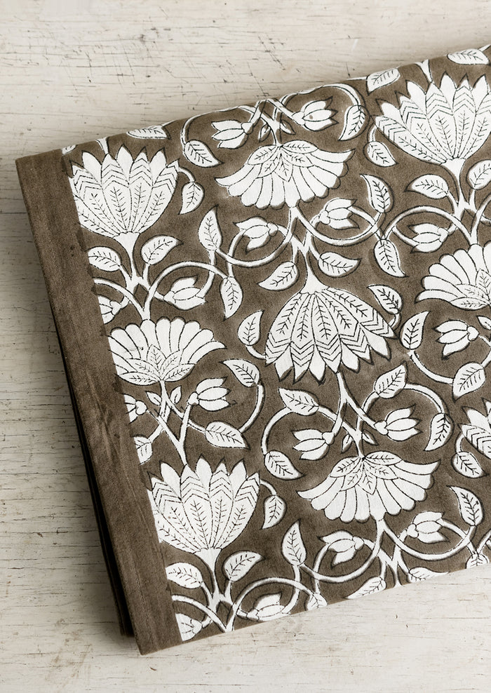 A block printed tablecloth with white lotus print on brown background.