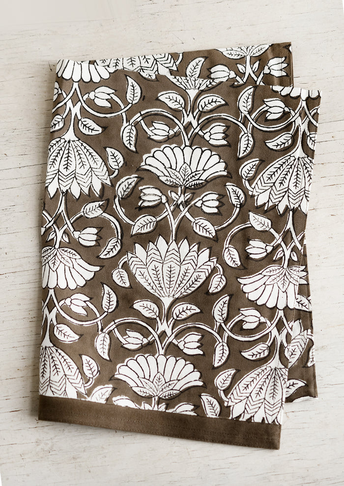 A dark brown and white lotus printed tea towel.