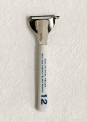 A vegetable peeler with ceramic white and blue handle with blue text.