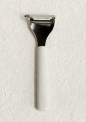 A vegetable peeler with ceramic white and blue handle with blue text.