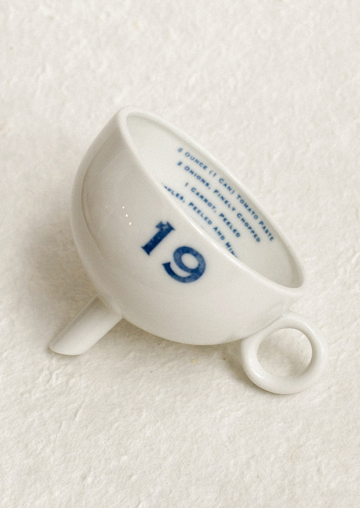 A ceramic funnel in white with printed blue text.