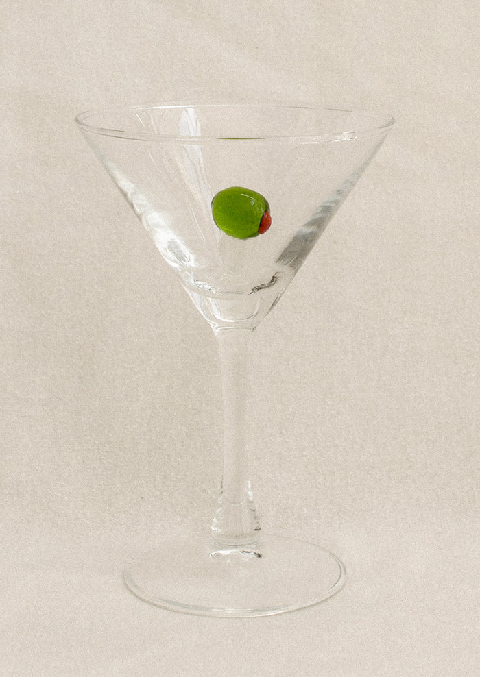 Clear martini glass with a glass olive decoration inside.