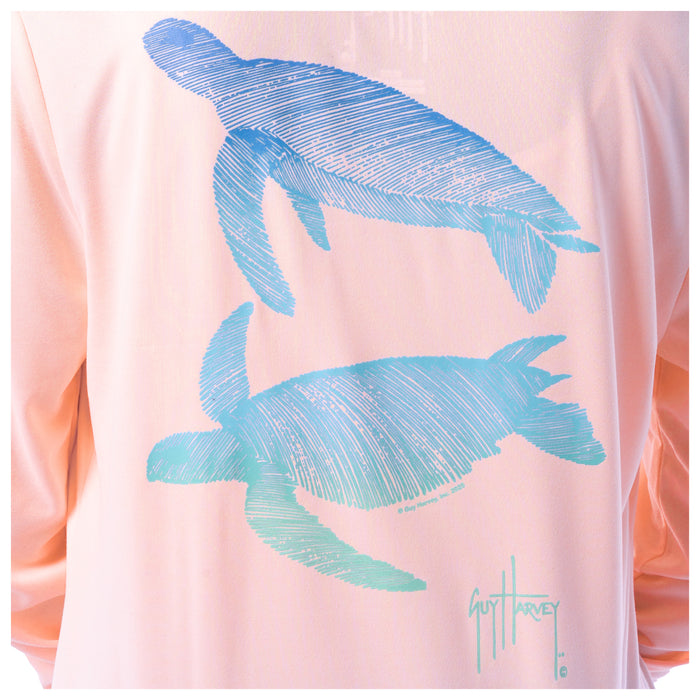 Pink shirt with blue turtle silhouettes and a signature on a white background
