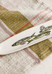 A long and skinny white ceramic dish with green sardine print.